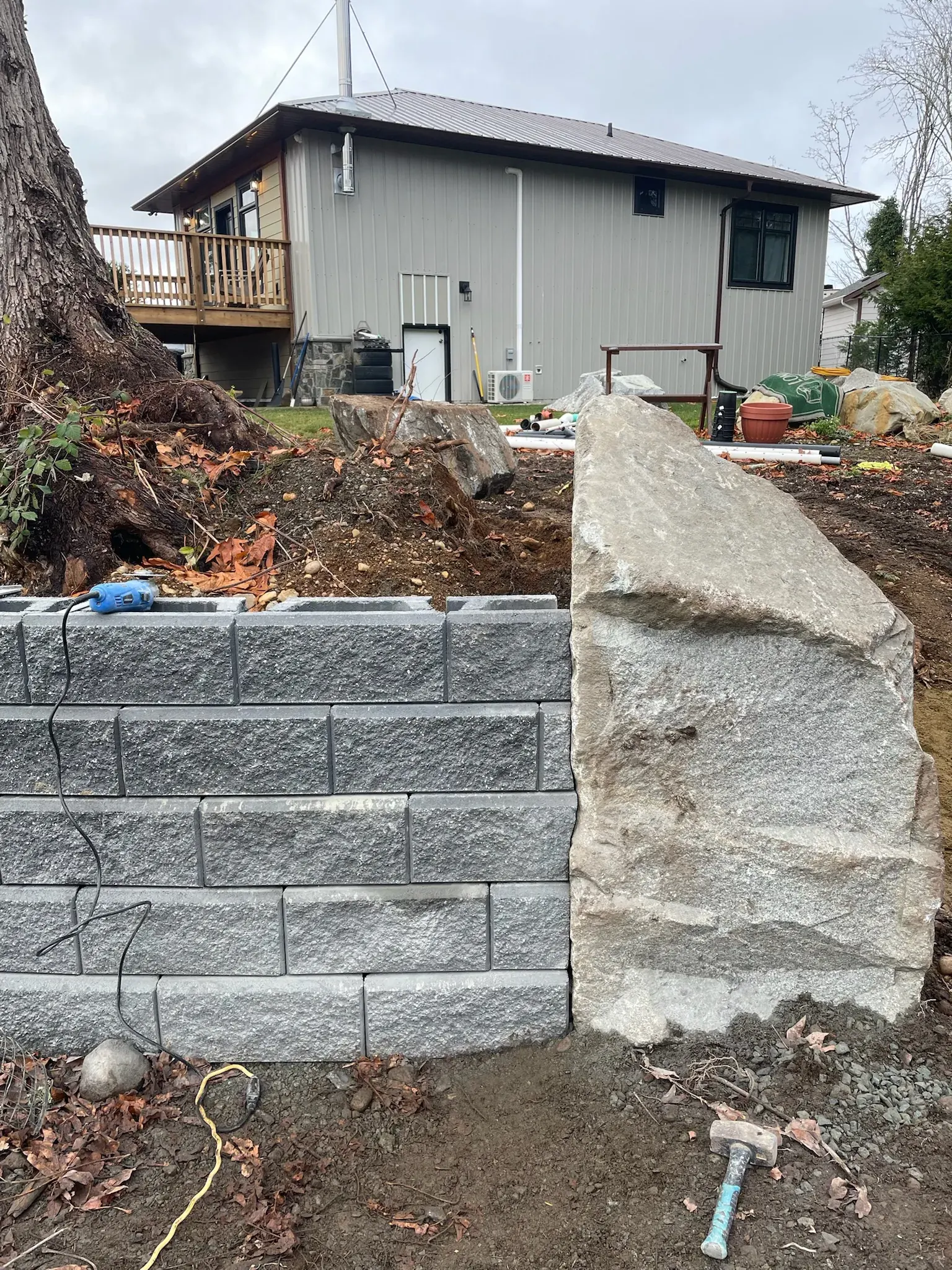 Block retaining wall under construction against a cut bank