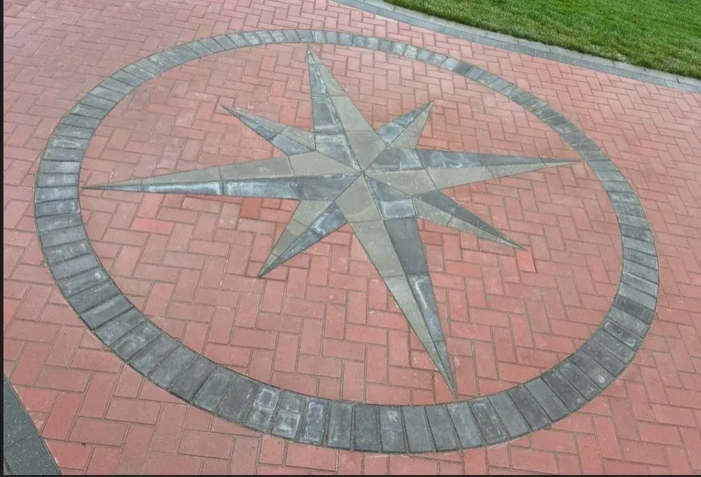 Cut-stone compass rose inlaid into a brick driveway
