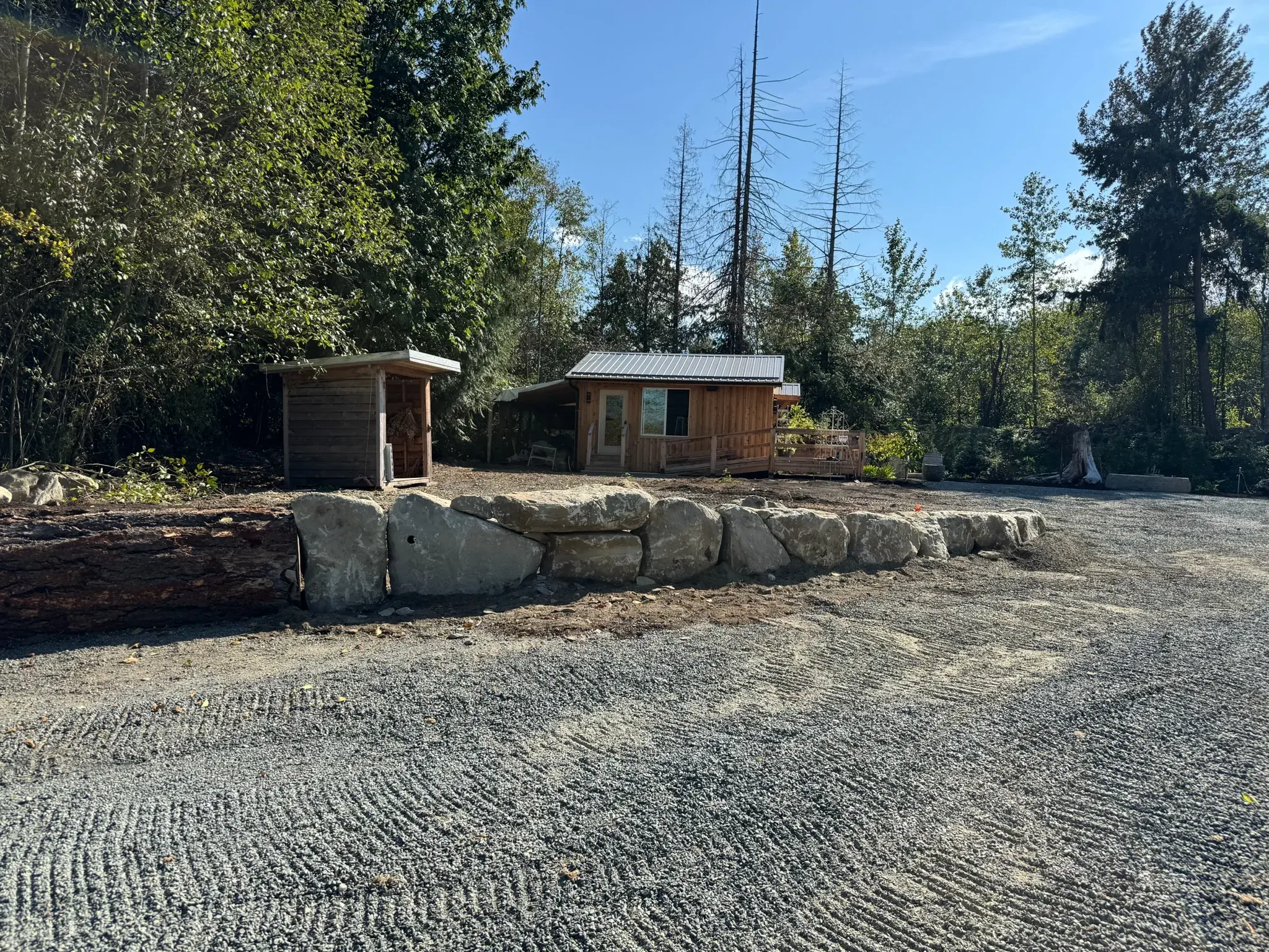 Freshly graded gravel driveway beside a new rock retaining wall