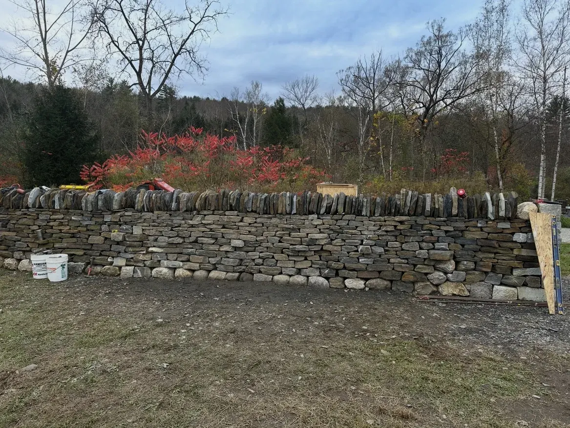 Long dry-stacked stone retaining wall built along a bank