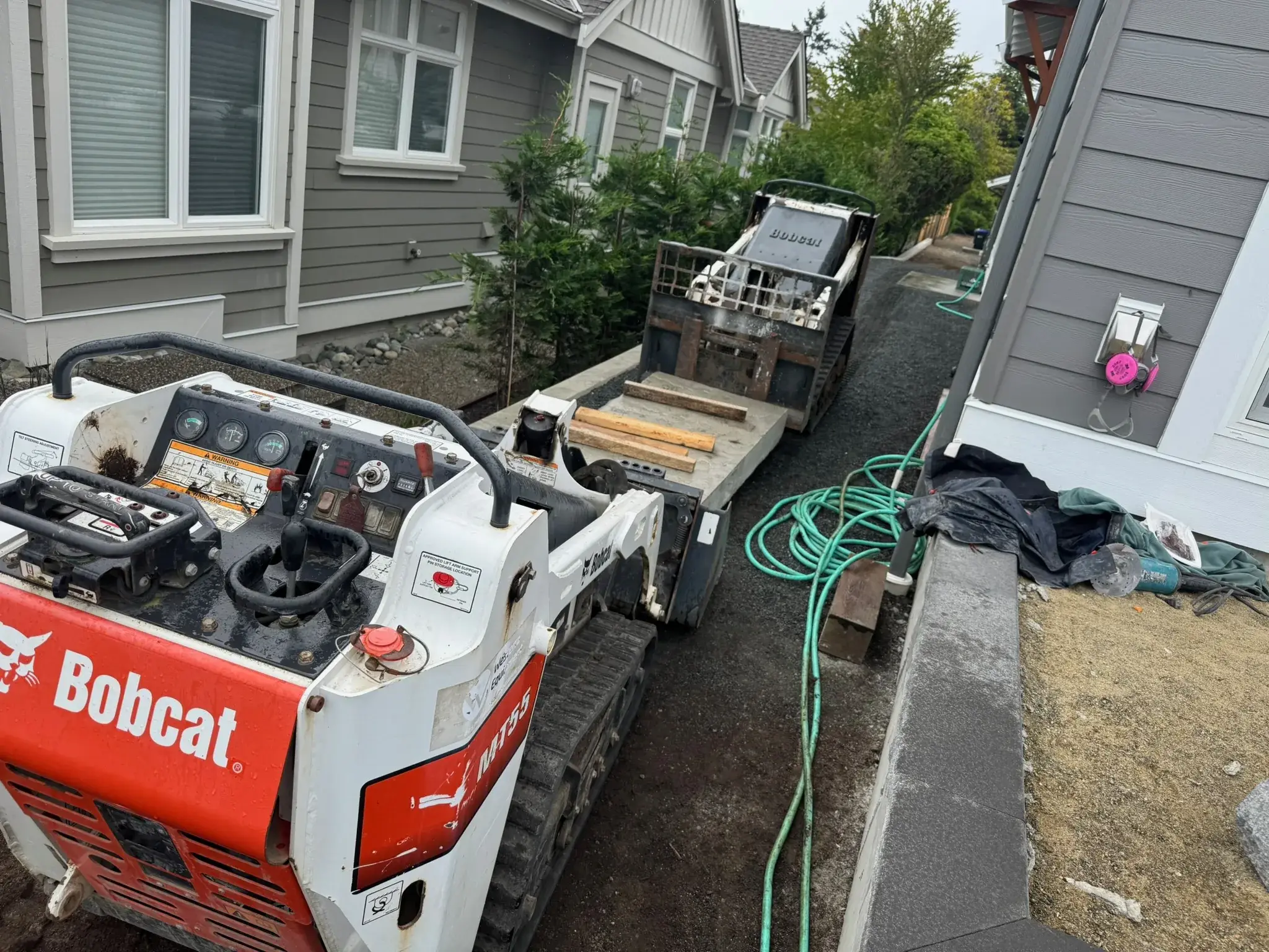 Tracked skid-steer working a tight side yard during site preparation