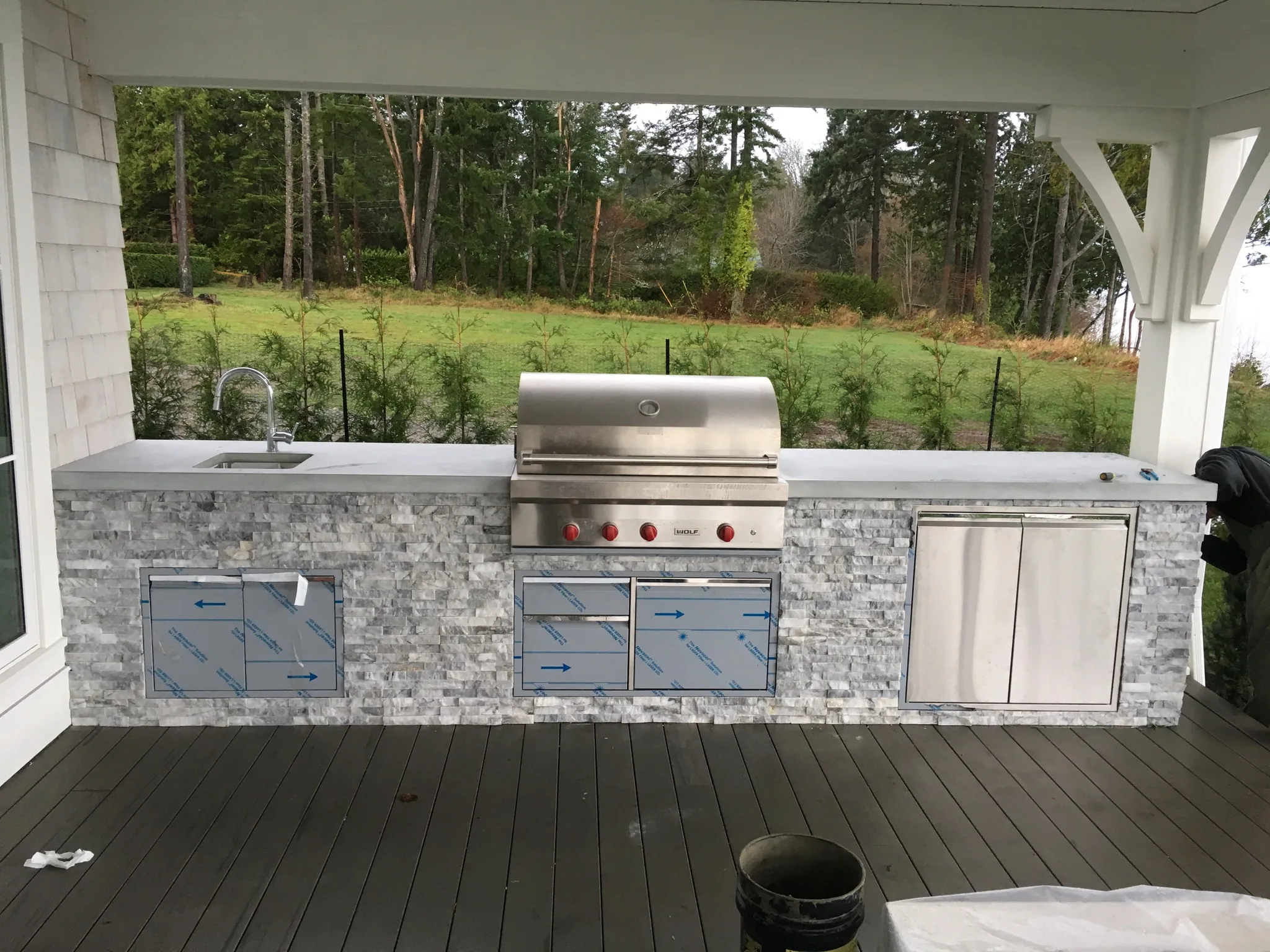 Built-in outdoor kitchen with grill and sink under a covered deck