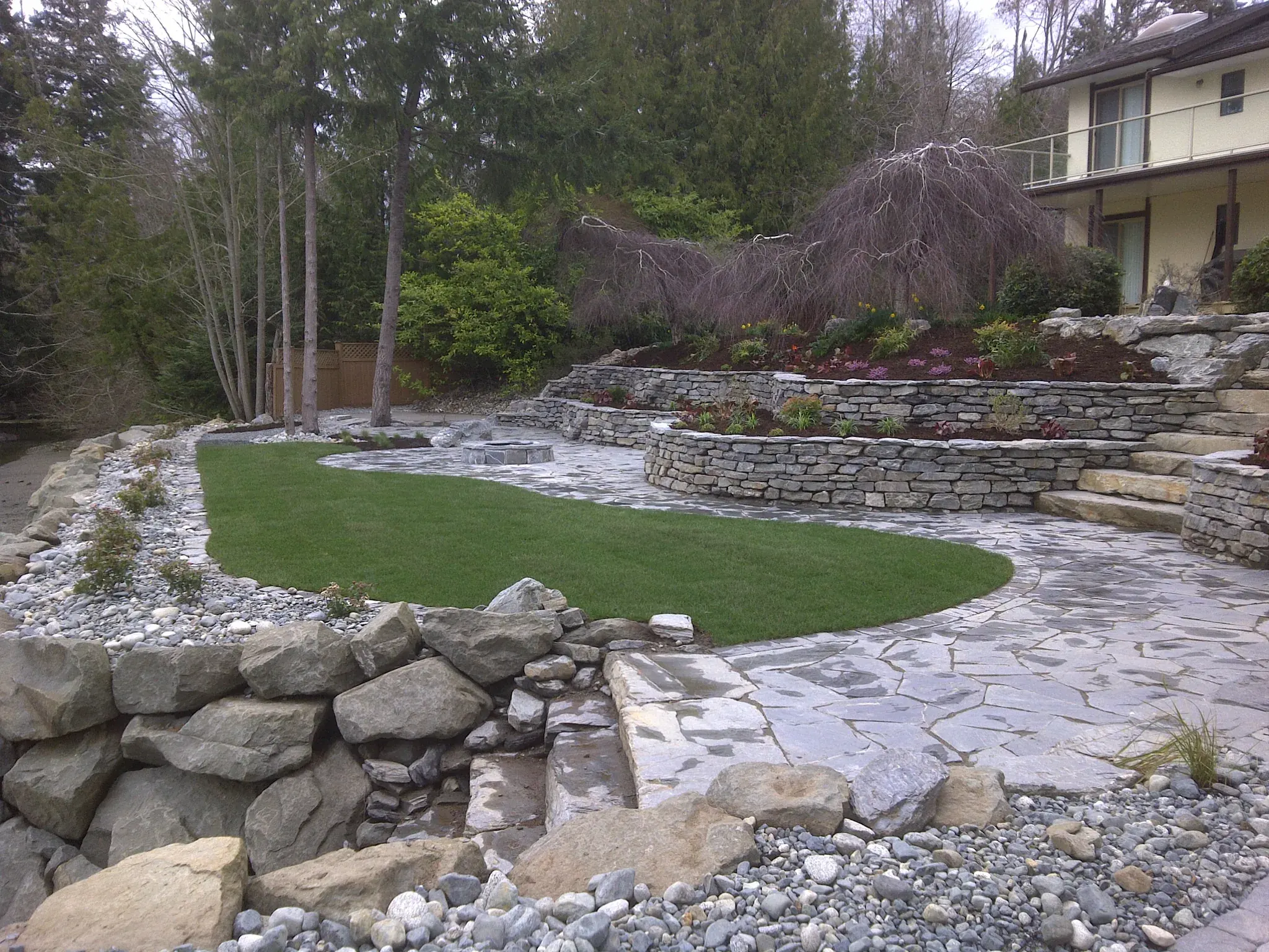 Stone terrace walls and lawn stepping down toward the water