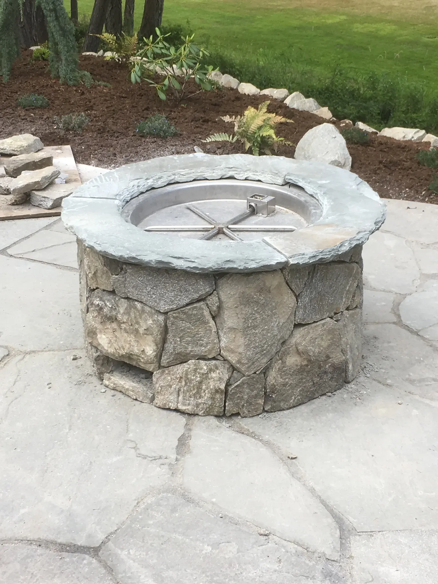Round stone fire pit set on a flagstone patio