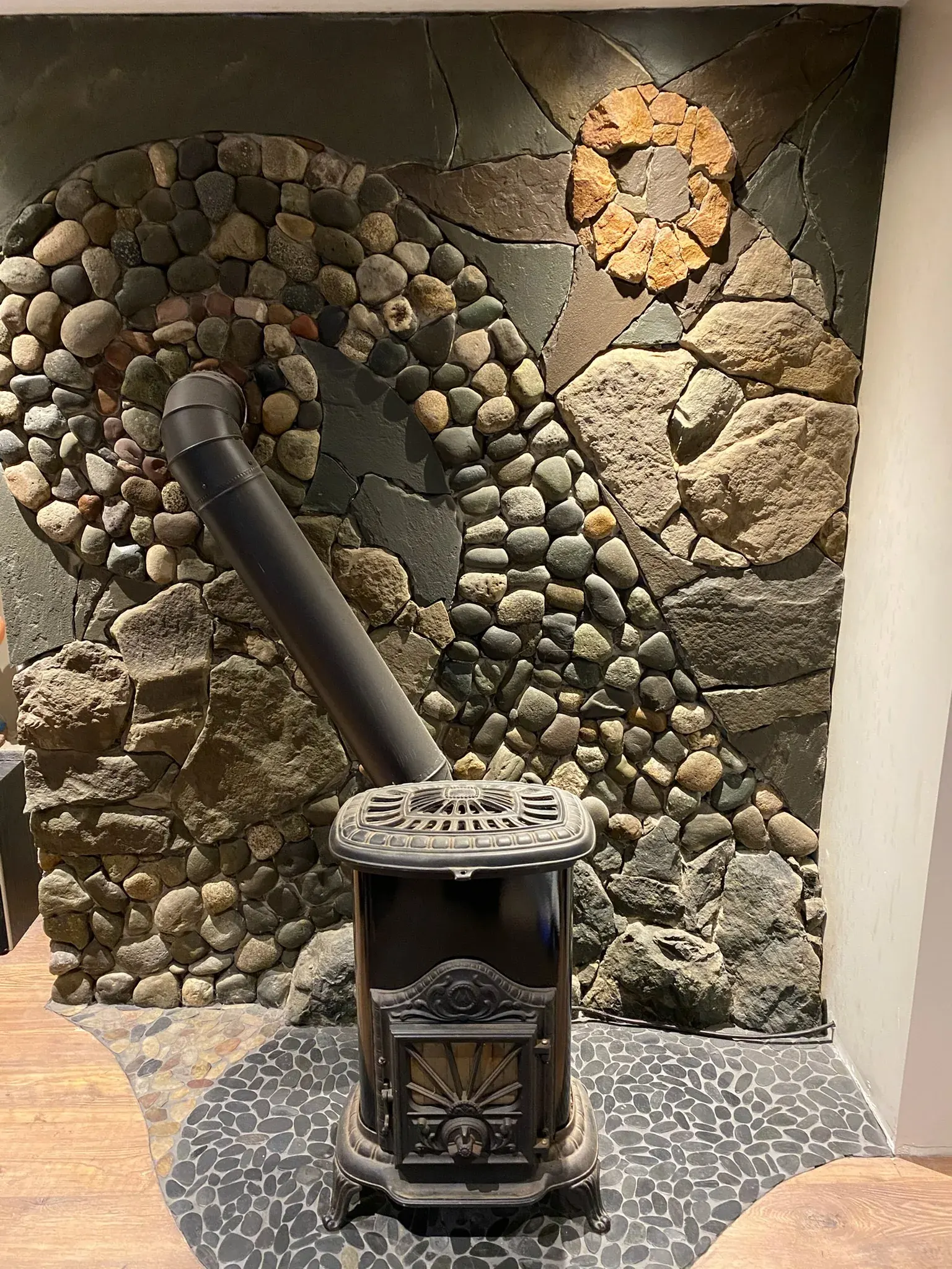 River-rock and stone mosaic surround built around a wood stove