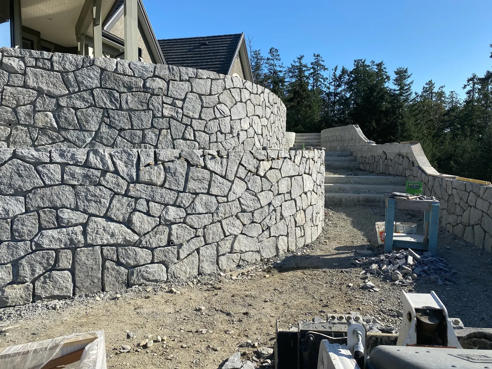 Tall stone retaining wall and steps under construction