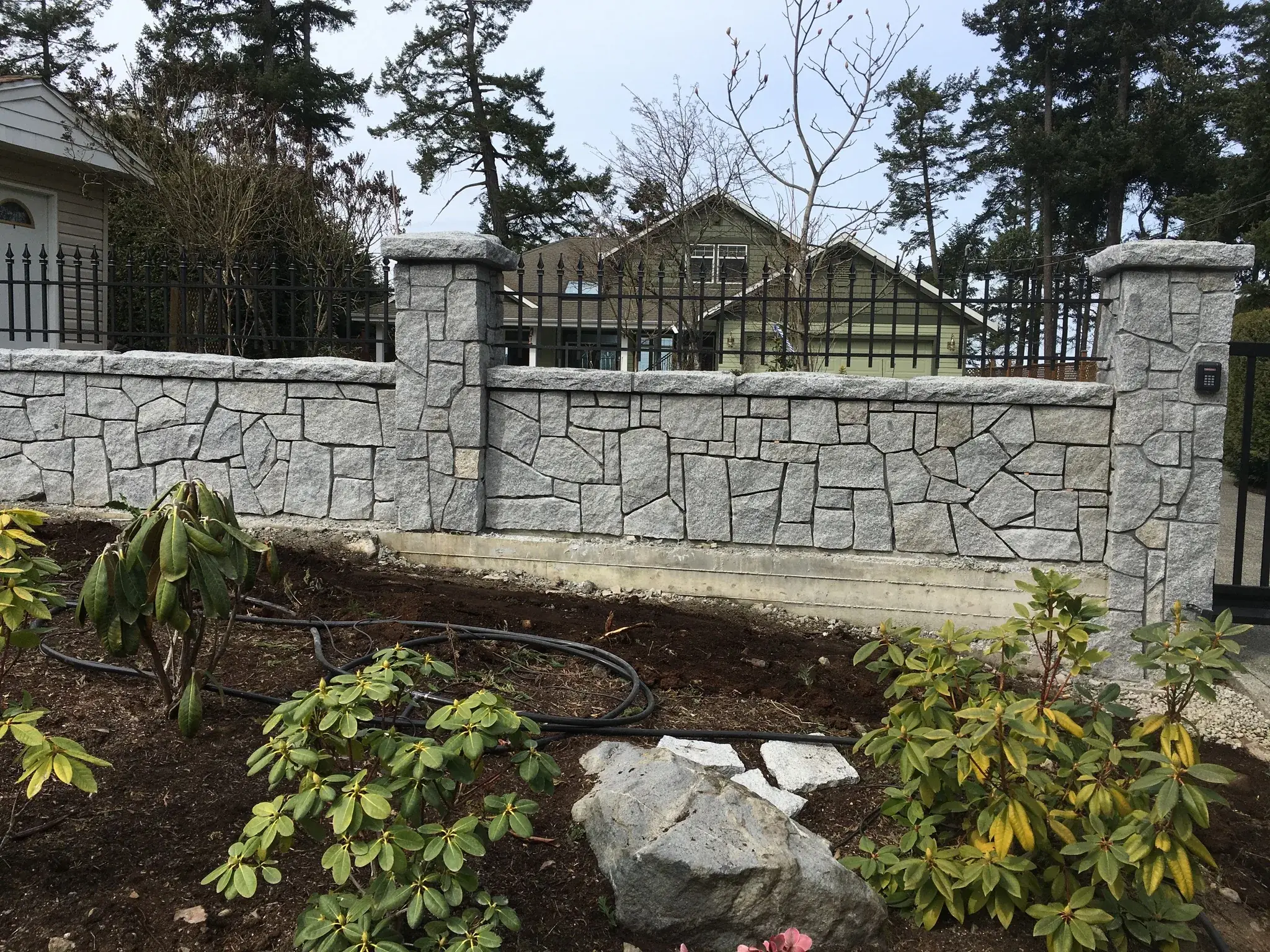 Mortared stone wall and pillars running along a new planted bed