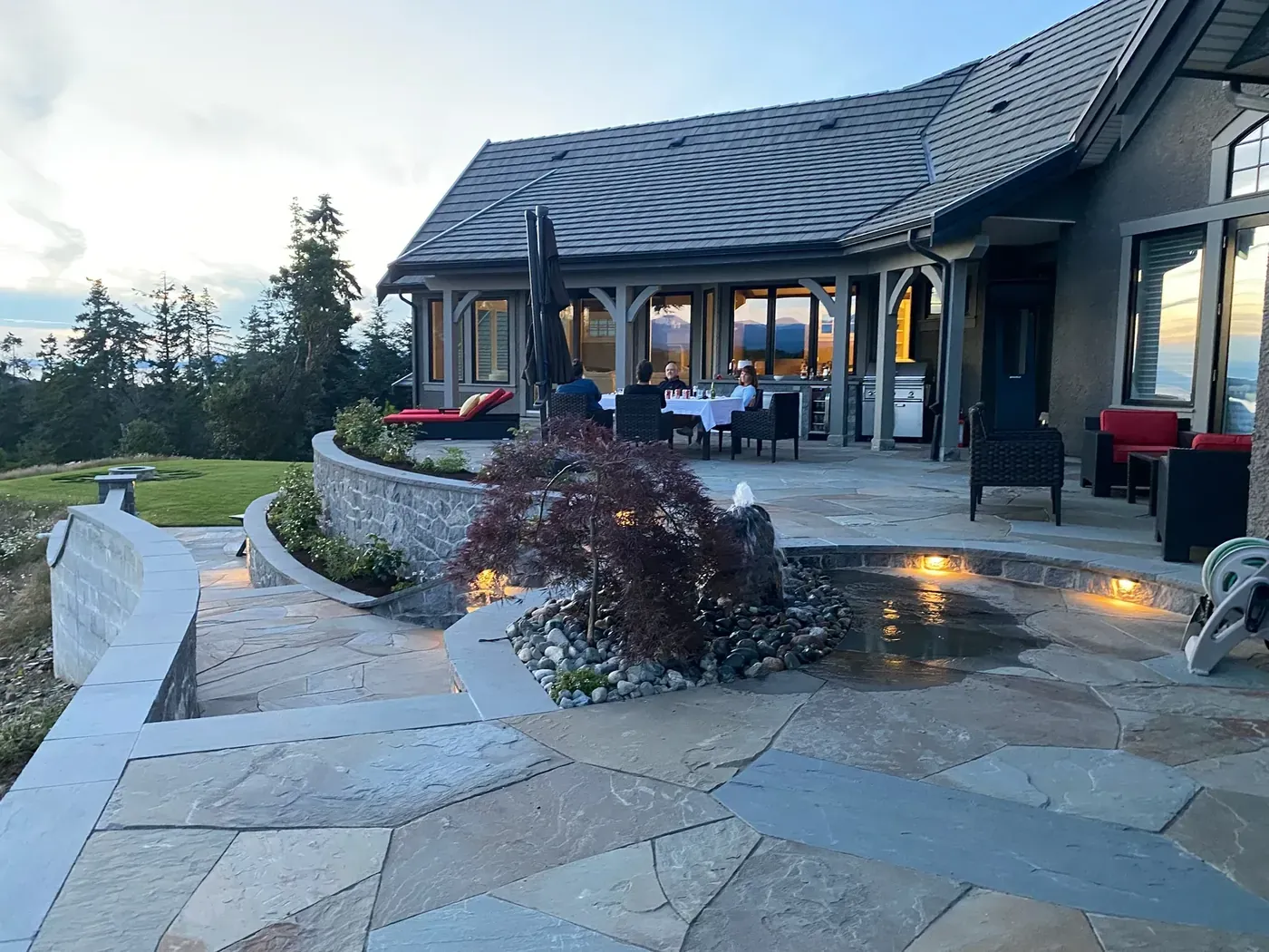 Stone patio and planted beds lit at dusk