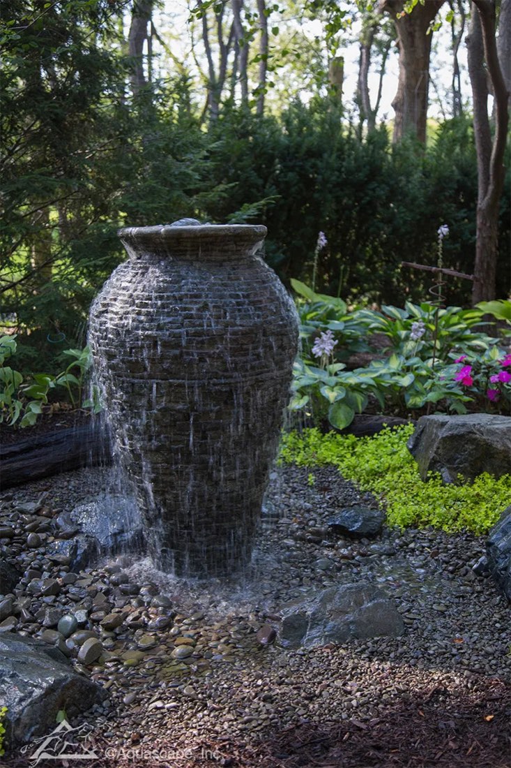 Stacked slate urn fountain installed in a garden bed